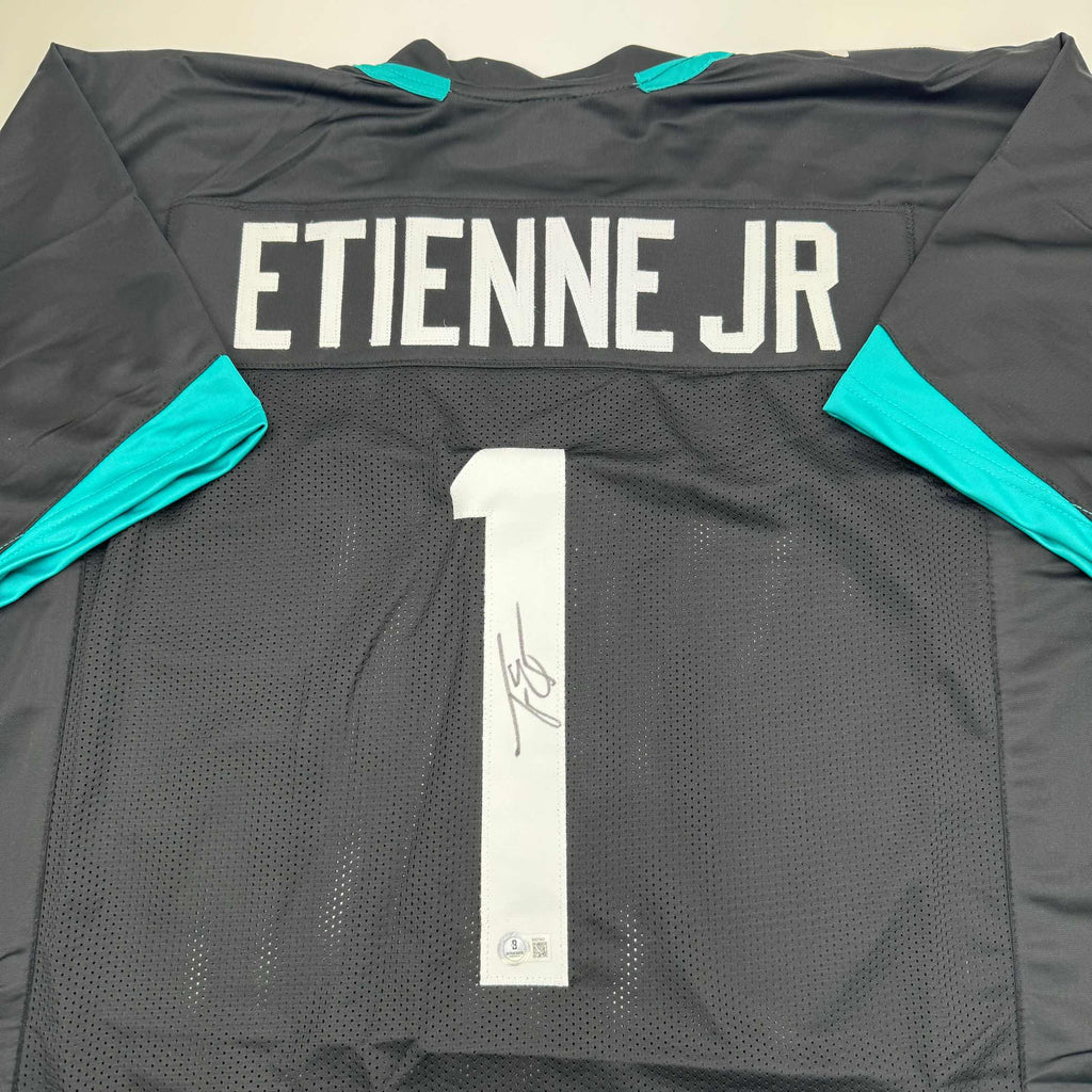 autographed-signed-travis-etienne-jr-jacksonville-black-football-jersey-beckett-bas-coa